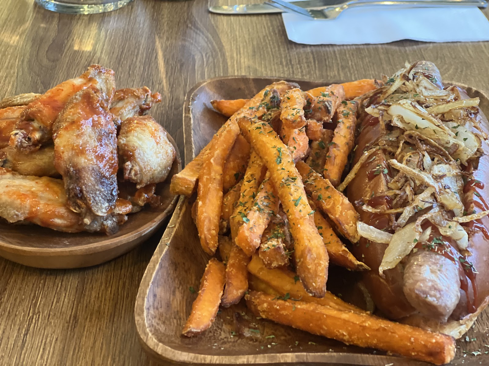 Pub plates from the kitchen — chicken wings and a hot dog piled with crispy onions over a bowl of sweet potato fries (photo: The Malt Man)